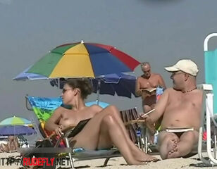 Big-chested doll sunbathing in a naked beach